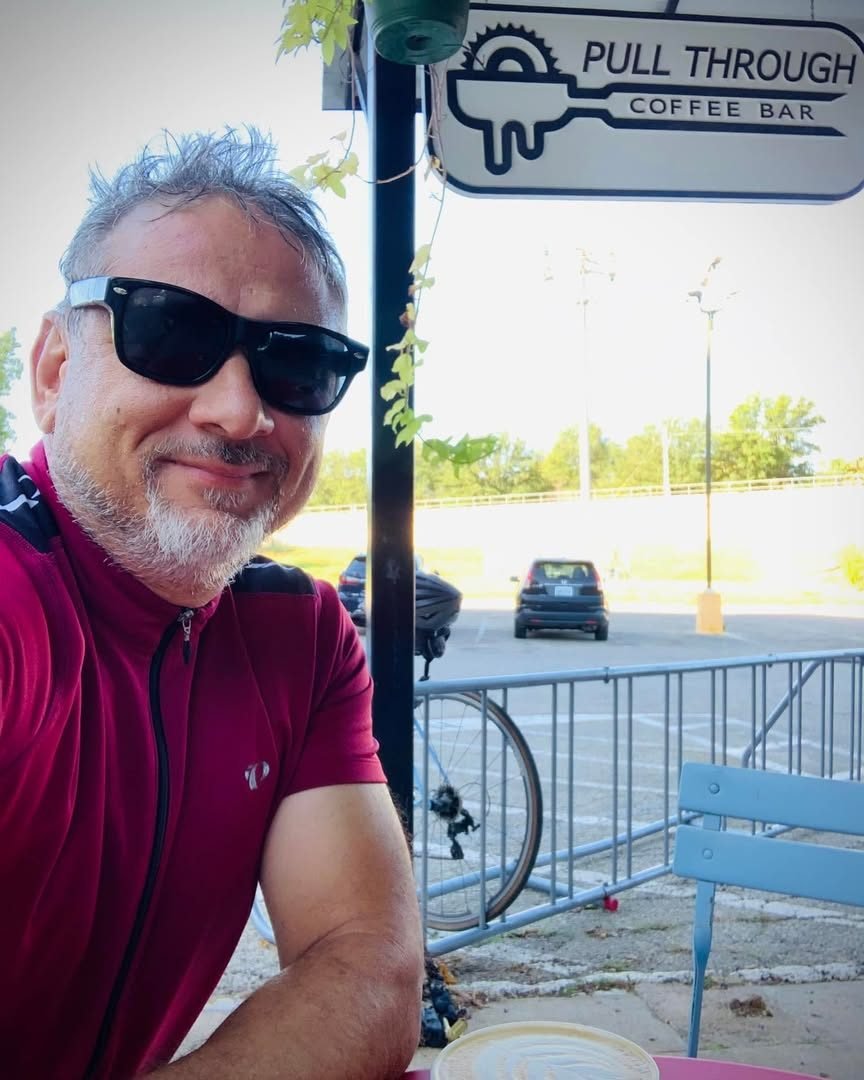 Lorne McMillan in a cycling jersey at Pull Through Coffee Bar, with his bicycle behind him